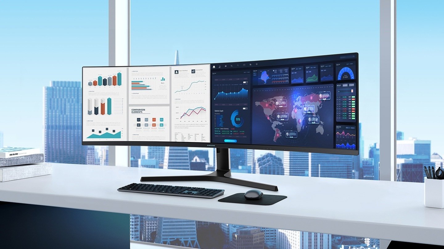 Samsung curved monitor with split screen sitting on desk with skyscraper view out of window in the background