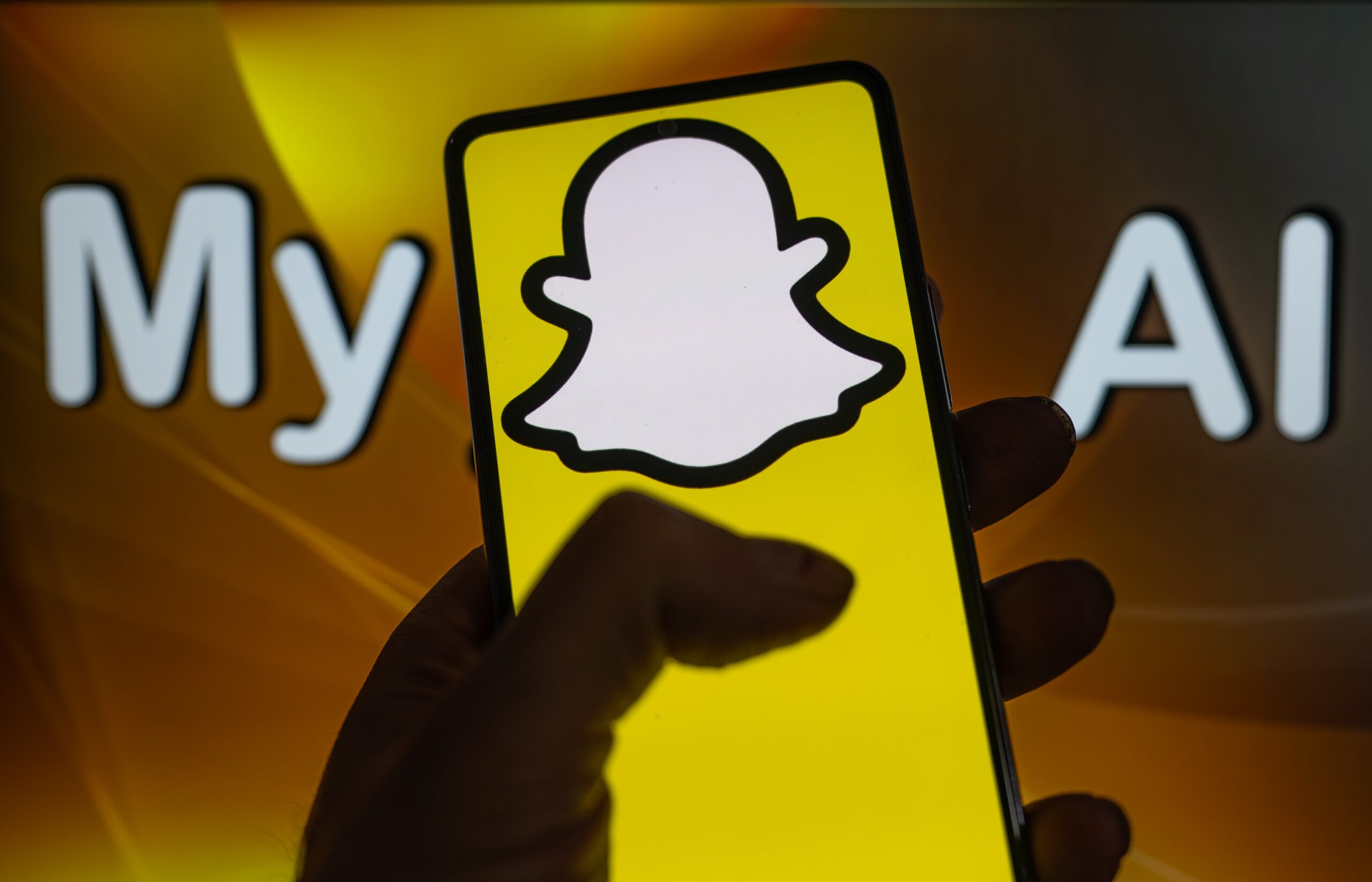 A phone displays the Snapchat logo in front of a screen that reads 