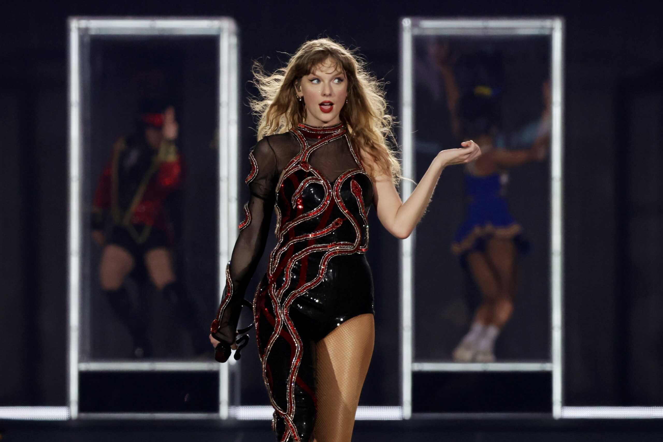Taylor Swift performing at The Eras Tour in a black and red jumpsuit giving major side eye.