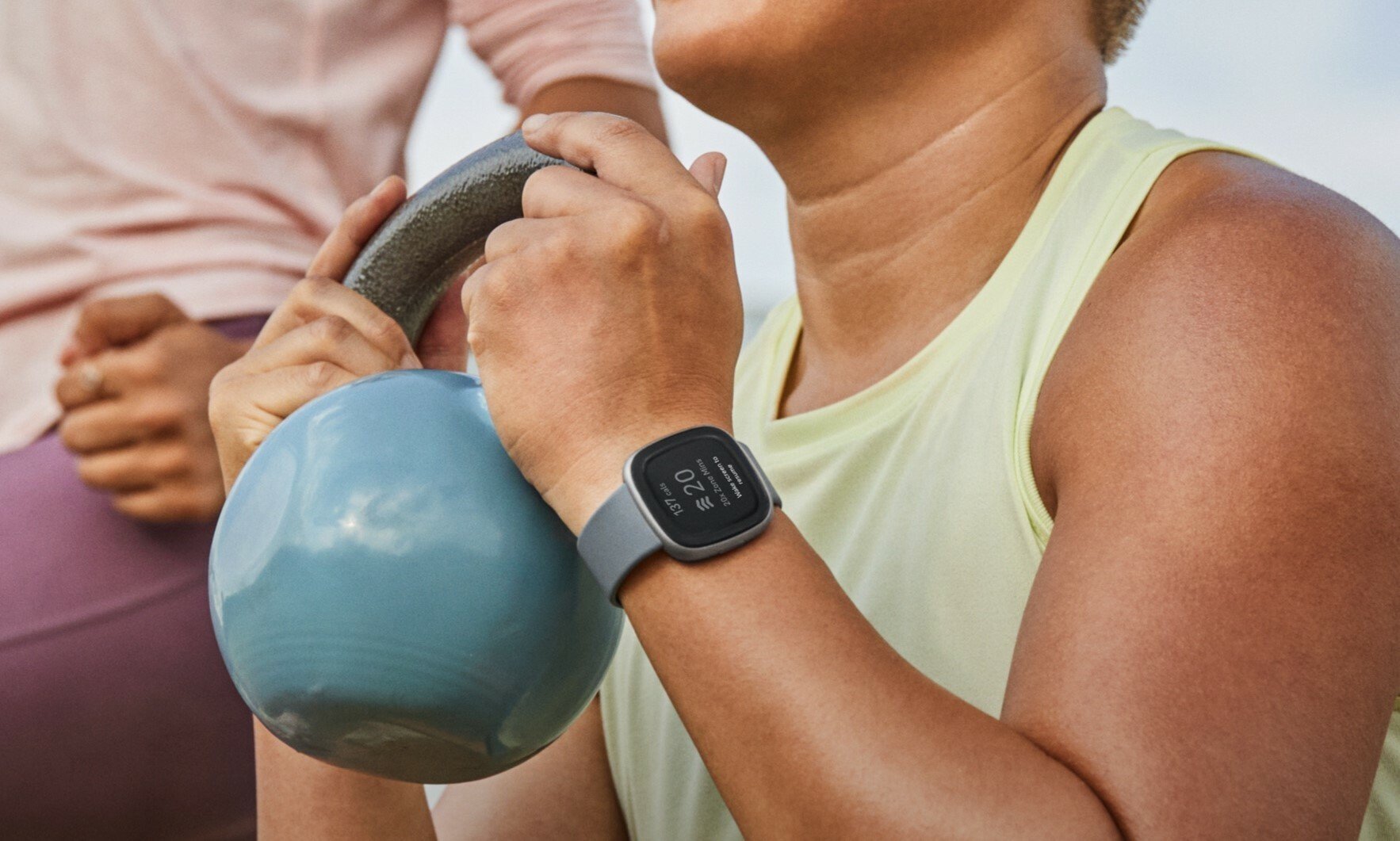 a person working out while holding a kettlebell is wearing a fitbit fitness tracker