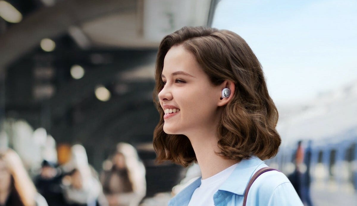 a person stands in near others while outside with the anker soundcore space a40 earbuds in her ears