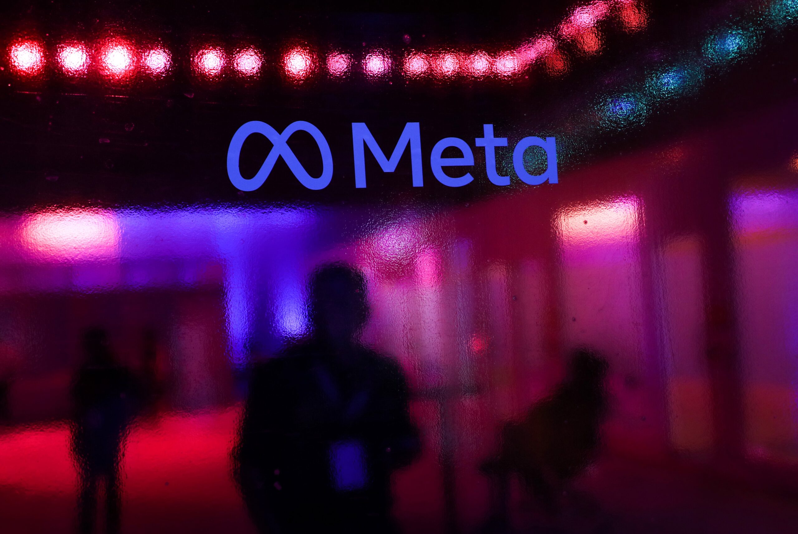 the Meta logo on a wall with a blurry reflected background
