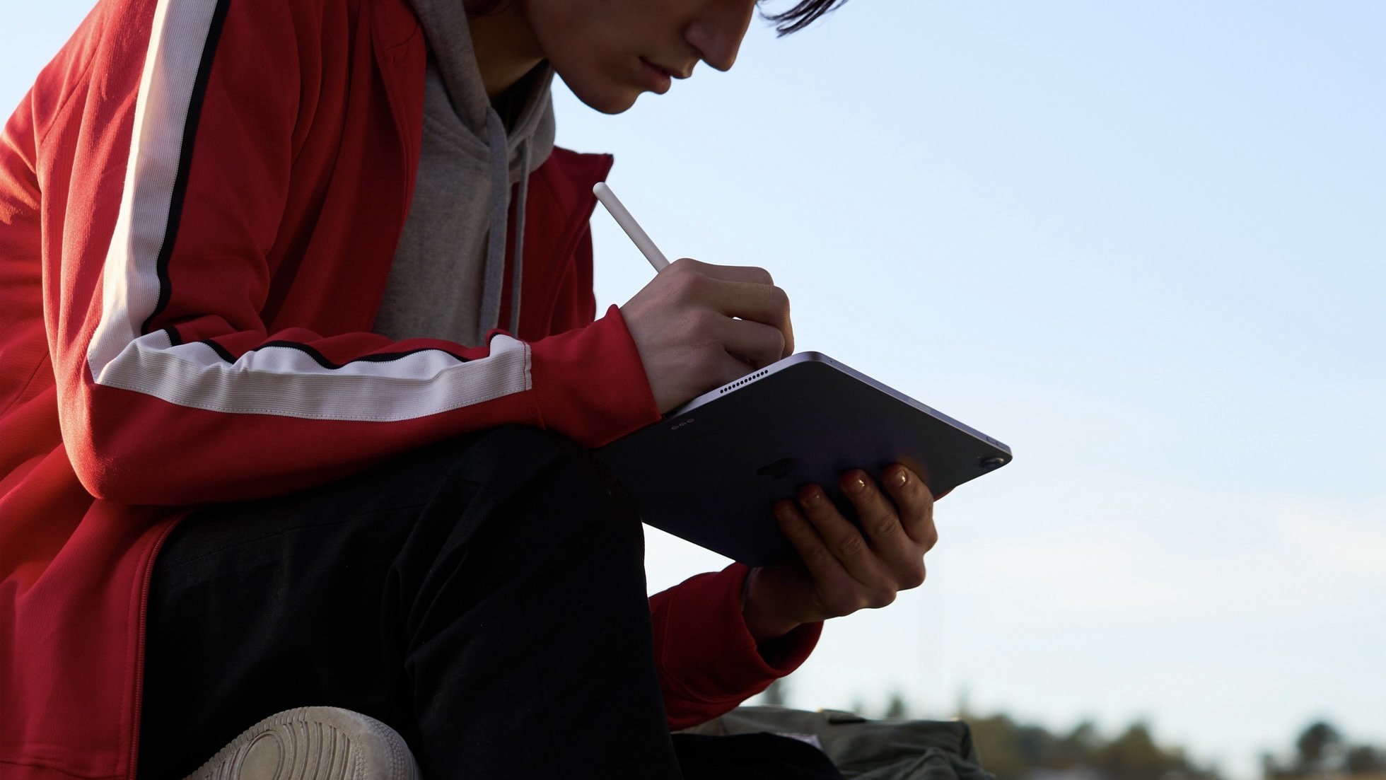 person sitting outside using apple pencil with ipad air