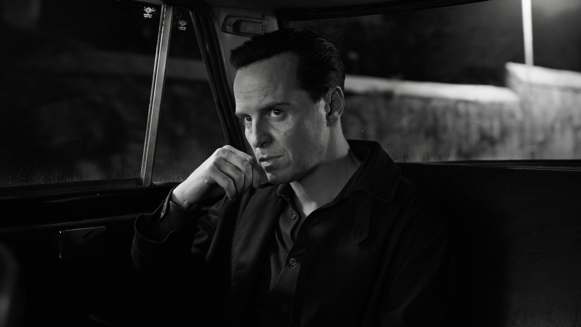 A man sits in a dark taxi looking intense.