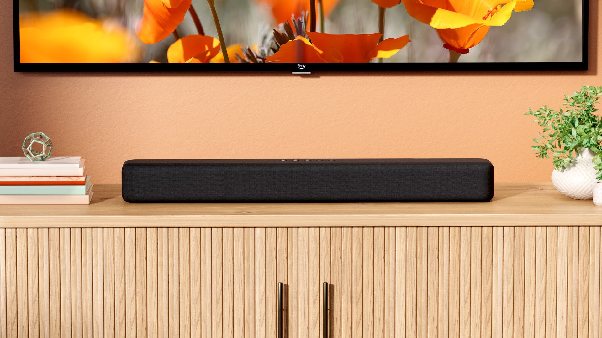 An Amazon Fire TV soundbar sits on a TV stand 