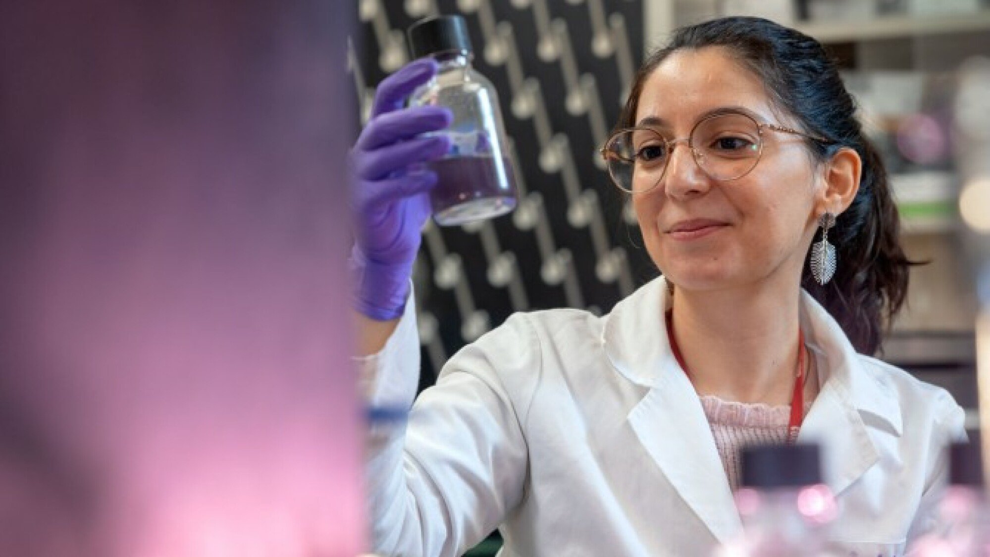 Lígia Fonseca Coelho holding a sample filled with purple-pigmented bacteria.
