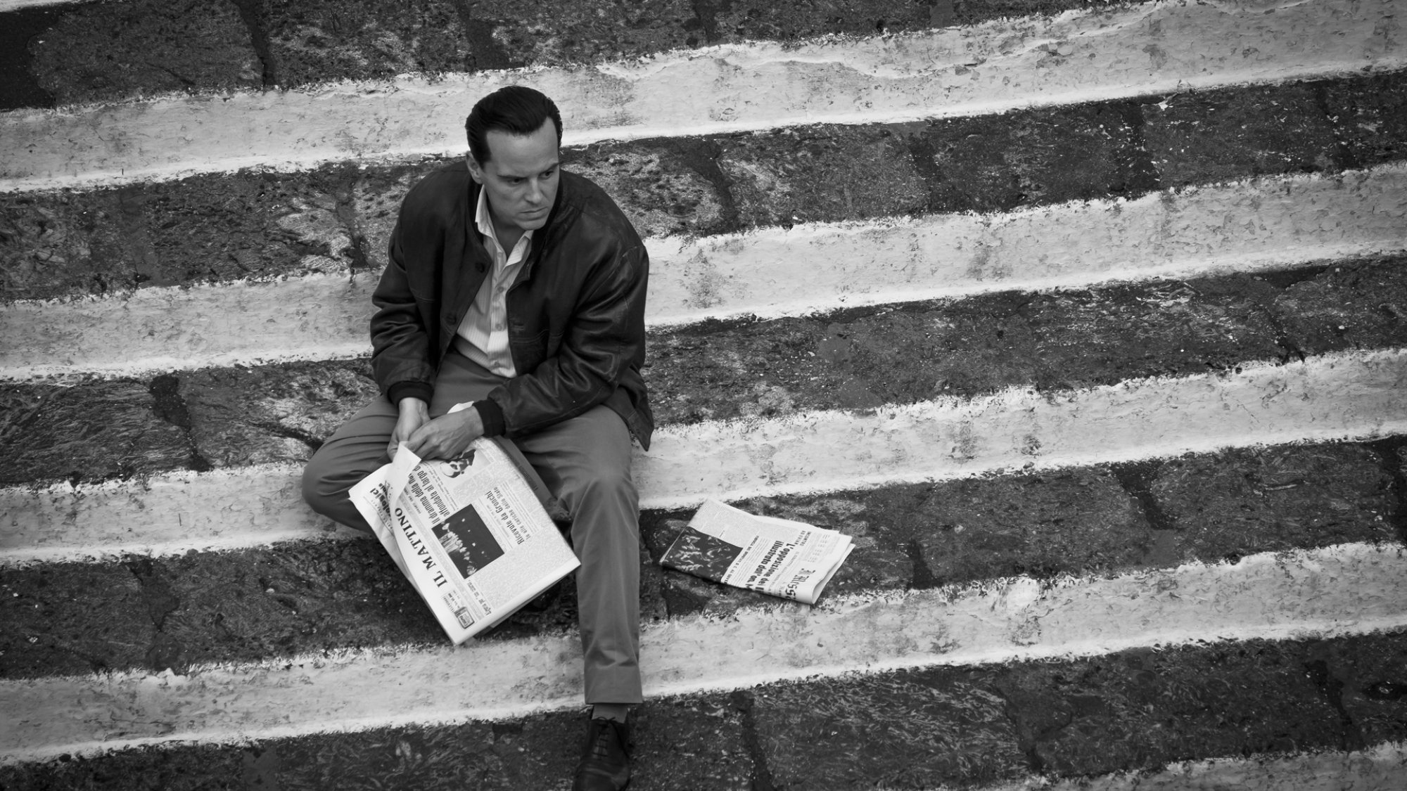A man reads the paper on a staircase.