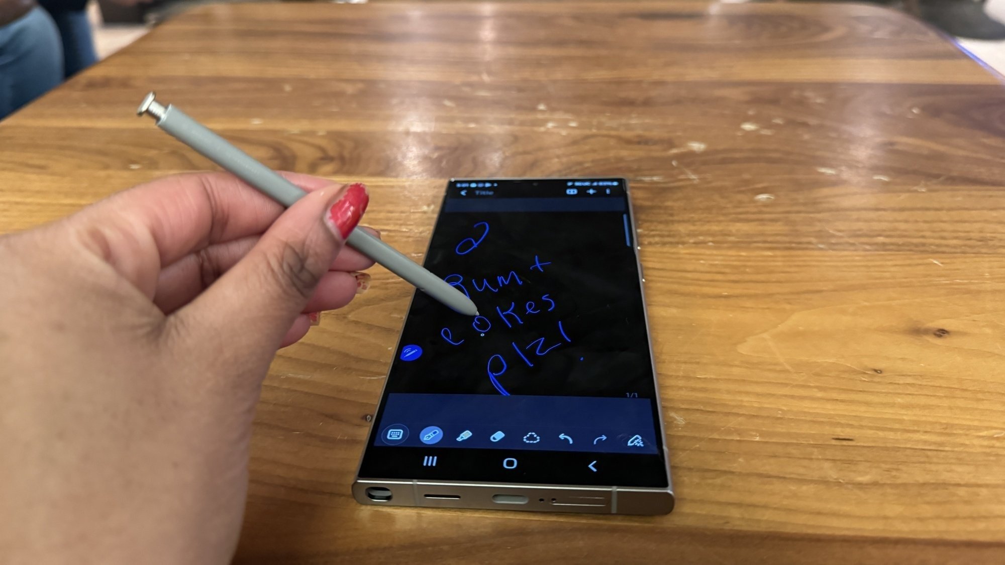 Samsung Galaxy S24 Ultra on a table with S Pen in a woman's hand