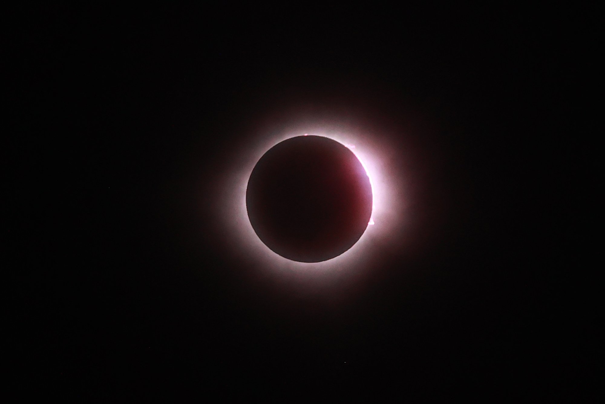 The sun fully disappears behind the moon during the solar eclipse on April 08, 2024 in Mazatlan, Mexico. The light behind the moon is bright and purple-ish..