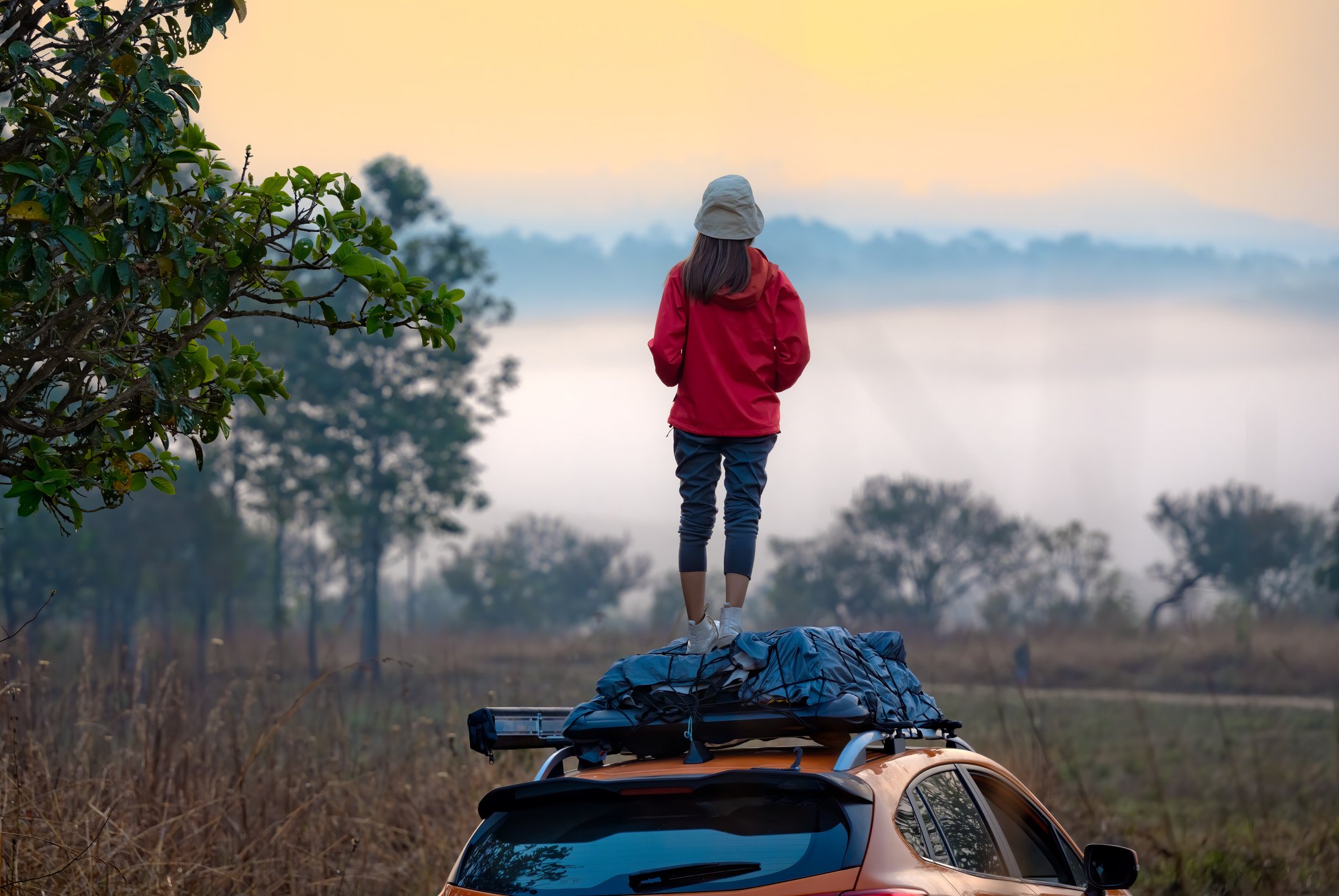 woman standing on car at sunset