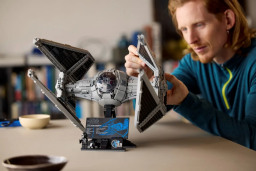 a man building the 2024 TIE Interceptor lego star wars set at a beige table