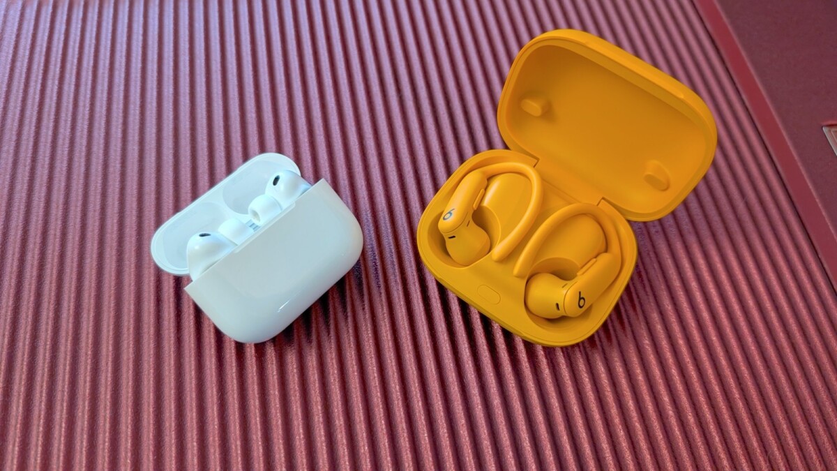 The Apple AirPods Pro 3 and the Beats Powerbeats Pro 2sitting on a red table