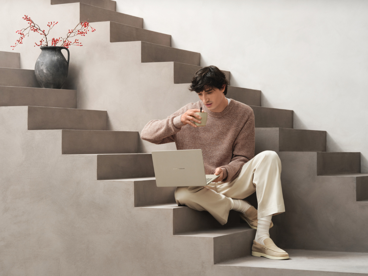 a man sitting on stairs while holding an asus zenbook a14