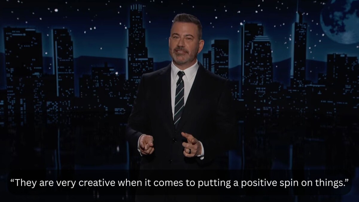 A man in a suit stands on a talk show stage. The caption at the bottom reads,