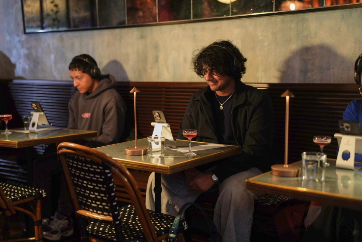 Customers sitting at small tables with phones on stands on them