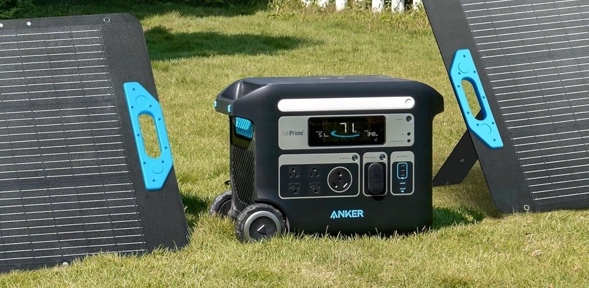 the anker solix f2000 portable power station on the grass sitting between two solar panlels